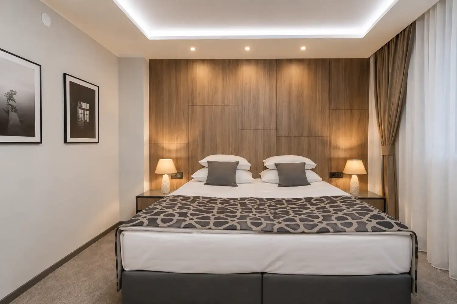 Large room with a king bed against a timber panelled wall and framed photography