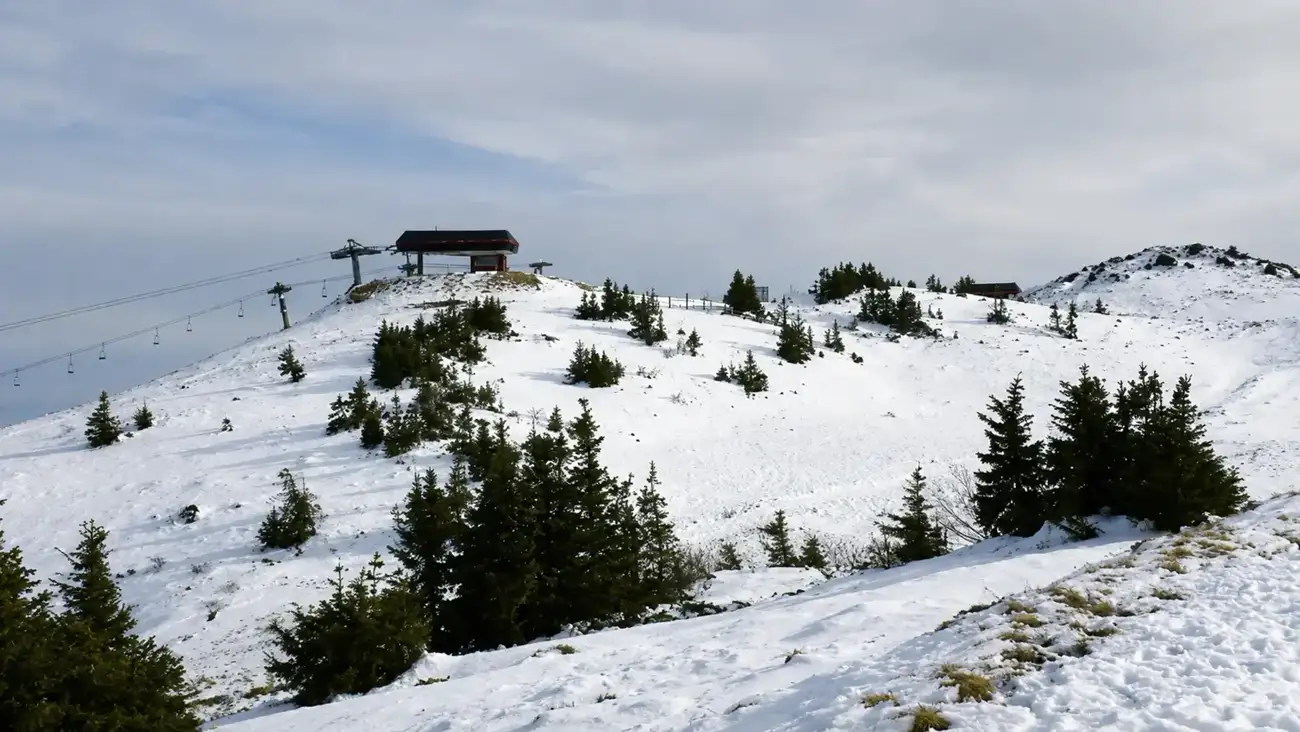 Snow-covered summit of Jahorina with a chairlift station and scattered pines