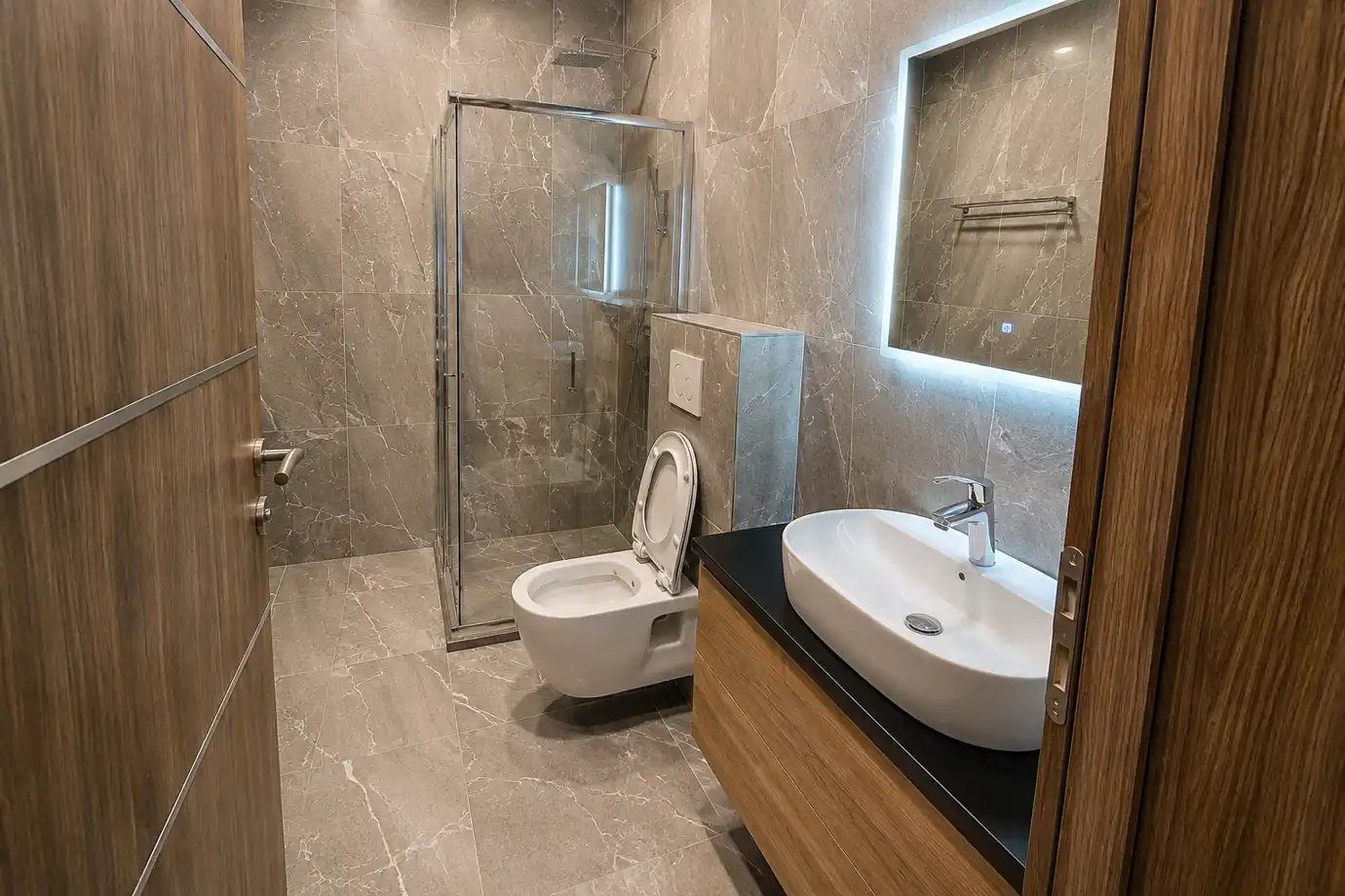 Guest bathroom with walk-in glass shower, stone tiling and a backlit mirror