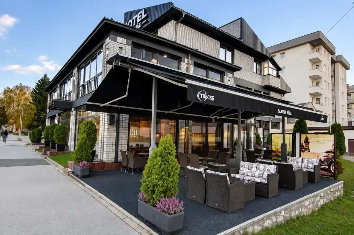Covered outdoor terrace of Hotel Zlatna Žita with wicker seating beside the entrance