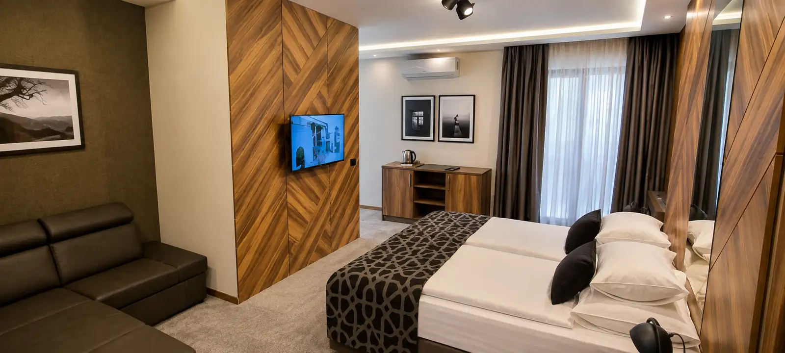 Modern guest room with timber panelling, sofa and made-up double bed