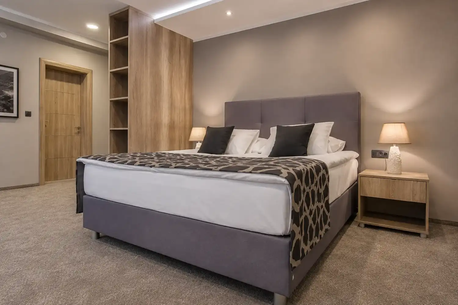 Double room with a king bed, patterned throw and warm bedside lamps
