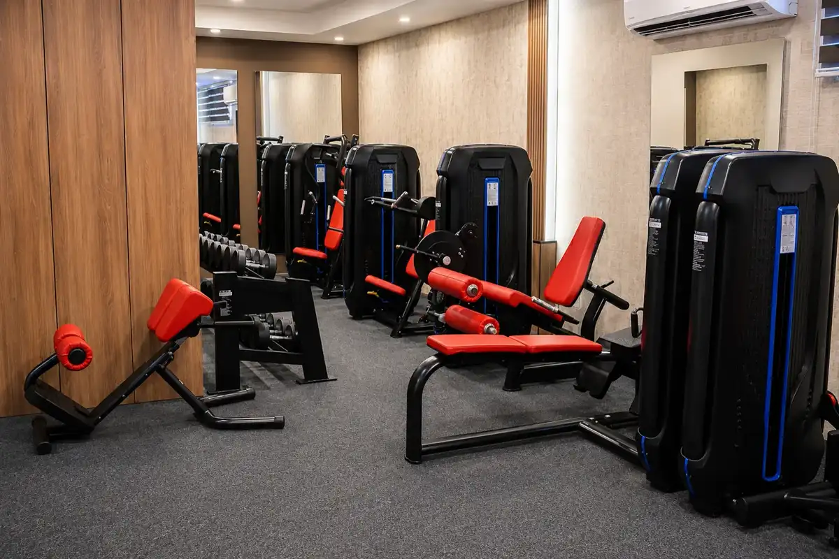 Fitness room with red and black weight machines, dumbbells and mirrored wall