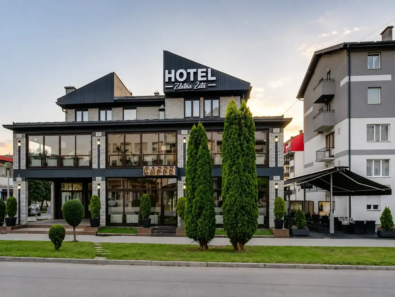 Facade of Hotel Zlatna Žita lit at dusk with its caffe windows glowing