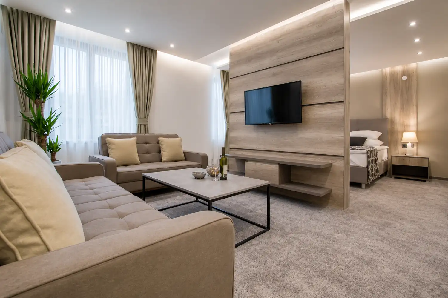 Bright apartment living area with sofas, coffee table and a view towards the bedroom