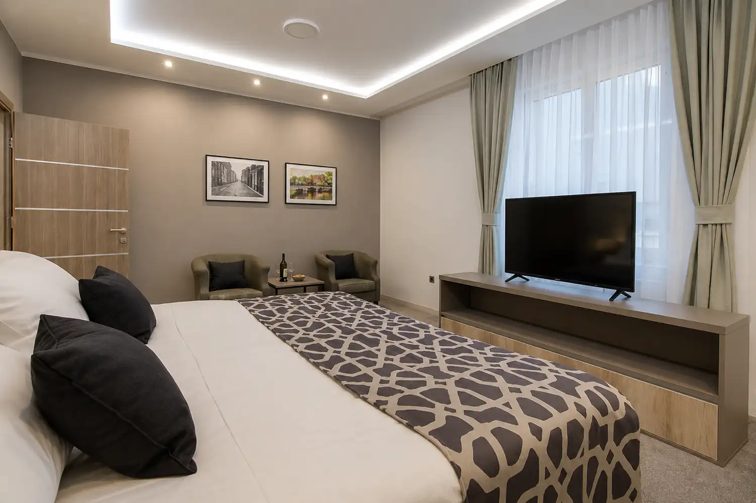 One-bedroom apartment with a king bed, armchairs and a television at Hotel Zlatna Žita